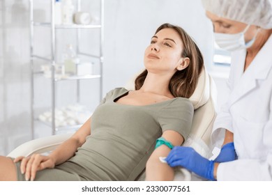 Young female patient having intravenously injection by nurse at treatment room of hospital - Powered by Shutterstock