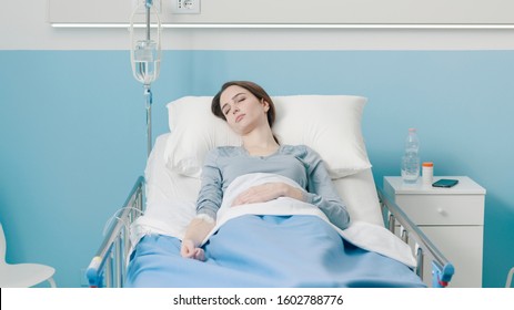 Young female patient lying in bed with IV drip, medicine and treatment concept - Powered by Shutterstock