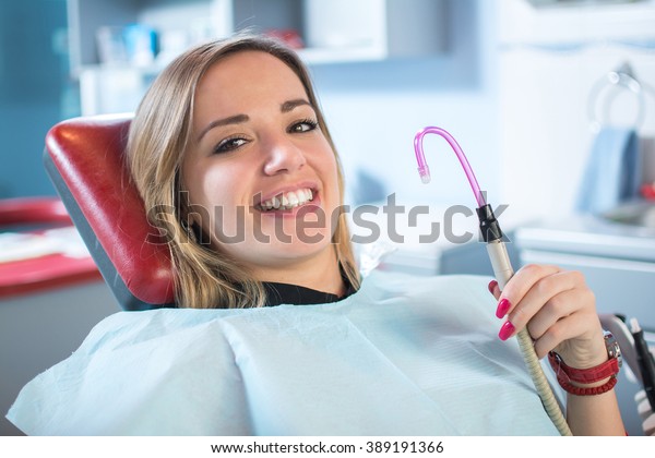 Young\
female patient smiling and holding suction tube.\
