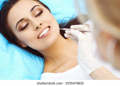 Junge weibliche Patientin, die Zahnarztpraxis besucht.Schöne Frau mit gesunden, weißen Zähnen, die auf einem Zahnstuhl sitzt, mit offenem Mund während der oralen Kontrolle während der Zahnarztpraxis