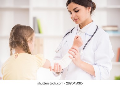 Young Female Pediatrician Doctor Bandaging Child's Arm.