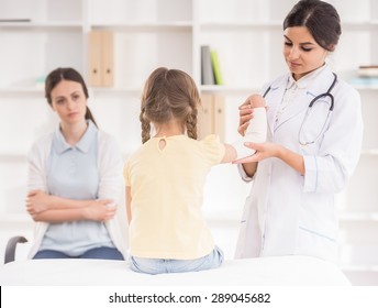 Young Female Pediatrician Doctor Bandaging Child's Arm.