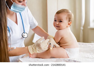 Young female pediatrician or nurse giving an intramuscular injection of a vaccine to leg of little baby boy Immunization for children concept. Happy little cute boy getting a flu shot not afraid of - Powered by Shutterstock