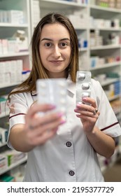 A Young Female Pharmacist Reads Medicine Instructions While Standing In The Chemist's Aisle. Pharmacy. Pharmacist. Medicine. Tablets