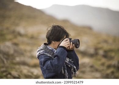 Young female photographer hiking in the mountains and taking landscape photos.