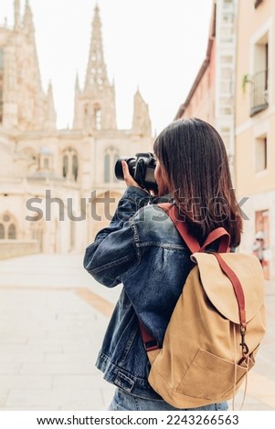 Young female photographer taking pictures with a digital camera in the city. Travel and active lifestyle concept