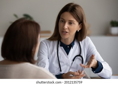 Young female physician asking older patient about complaints, instructing about treatment, giving consultation, recommendation at appointment in office. Retiree visiting doctor for health examination