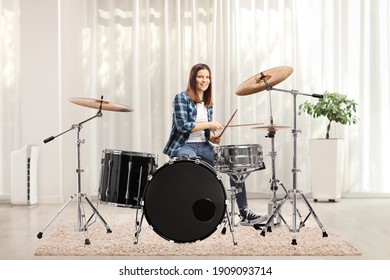 Young female playing drums at home