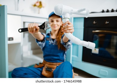 Young Female Plumber Shows Wrench And Pipe