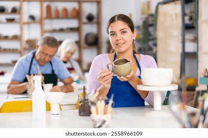 Young female potter student demonstrates pottery made by her own hands - Powered by Shutterstock