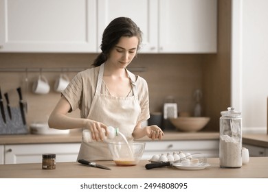 Young female pouring milk into bowl of beaten eggs, prepare omelet or dough for pastries, making homemade dish, enjoy process and homemade cookery process, trying new recipe. Routine, household chores - Powered by Shutterstock