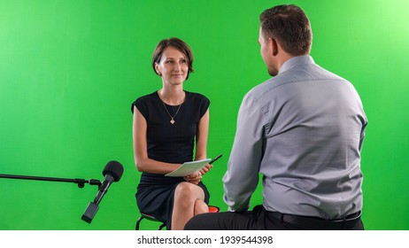 Young female presenter interviewing in television studio with green screen - Powered by Shutterstock