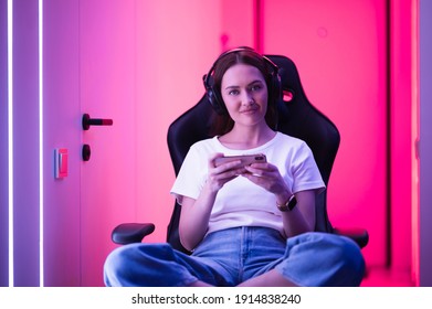 Young Female Professional Cybersport Gamer Play Mobile Game By Smartphone On ESport Tournament Online In Colorful Neon Lights Room.