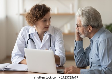 Young Female Professional Doctor Physician Consulting Old Male Patient, Talking To Senior Adult Man Client At Medical Checkup Visit. Geriatric Diseases Treatment. Elderly Medical Health Care Concept