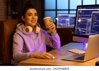 Young female programmer drinking coffee while working in office