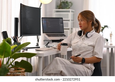 Young female programmer working with coded data on desktop computer in bright modern office