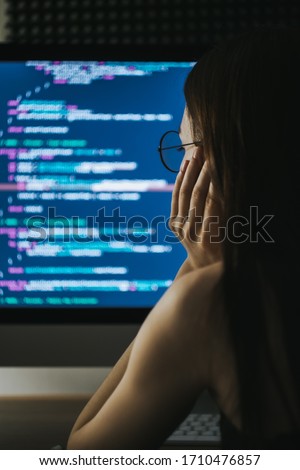 Young female programmer writes program code on a computer. home office