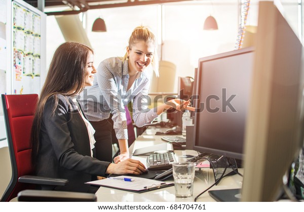 Young female programmers working together on desktop computer inoffice