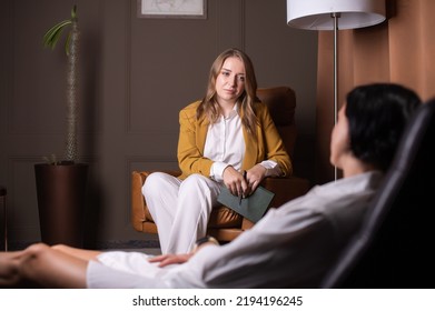 A Young Female Psychologist Listens Attentively To A Client Sitting On A Couch