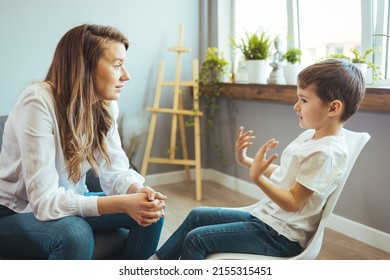 Young female psychologist working with little boy in office. Shot of a young child psychologist talking with a boy. Young female school psychologist having serious conversation with smart little boy - Powered by Shutterstock