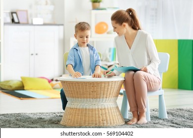 Young female psychologist working with little boy in office - Powered by Shutterstock