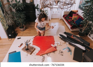 Young female purse maker working with leather textile at her workshop.Piece of red leather. Tailor,leather craftswoman making measurements. Crafting tools.Life is beautiful-print on t-shirt - Powered by Shutterstock