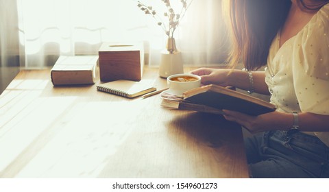 Young Female Reading Old Book And Drink Cofee After Work With Sunlight Through The Window In The Morning, Vintage Color Tone