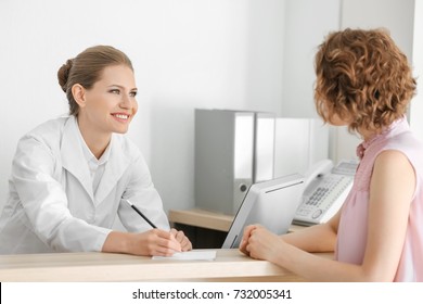 Young Female Receptionist With Client In Hospital