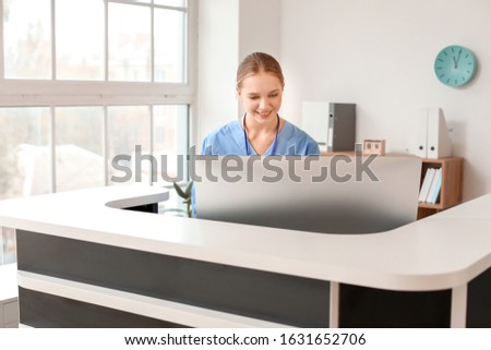 Young female receptionist working at desk in clinic
