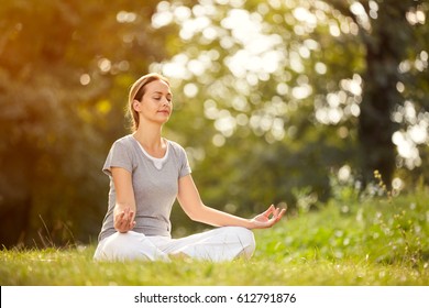 Young female relaxes in yoga pose in green nature - Powered by Shutterstock