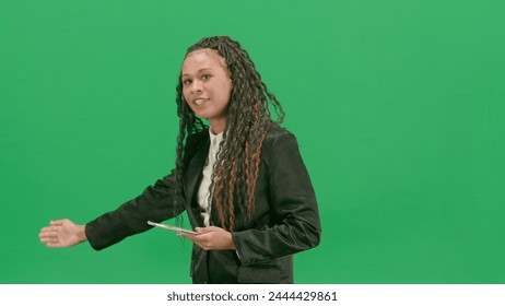 Young female reporter isolated on chroma key green screen background. African american woman tv news host holding tablet, shows empty area. - Powered by Shutterstock