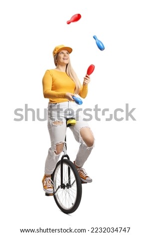 Young female riding a mono cycle and juggling isolated on white background