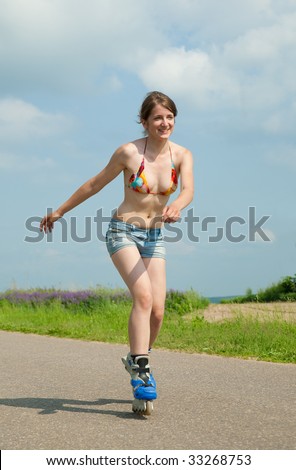 young female rollerskating on asphal road against nature
