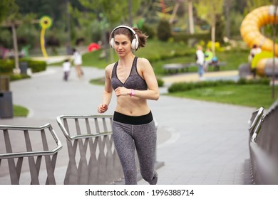 Young female runner, athlete is jogging in tpark in spring sunshine. Beautiful fit caucasian woman training. Concept of fitness, sport, healthy lifestyle, movement, activity and stretching