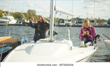 Young Female Sailing Athletes Sit On The Deck Of A Sports Yacht And Take A Selfie With A Victory Gesture.