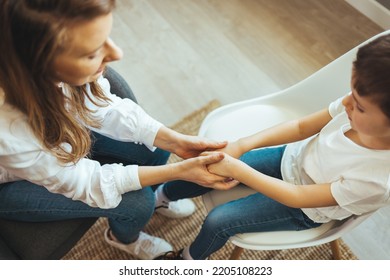 Young female school psychologist having serious conversation with smart little boy at office. Close up image mother and son palms, mommy holding hands of kid.  Concept of counsellor - Powered by Shutterstock