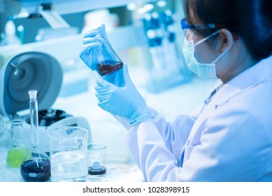 Young Female Scientist Looking At The Flask In Medical Laboratory. Researcher Concept.