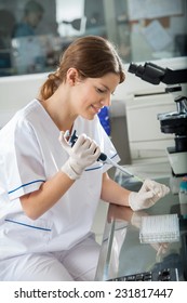 Young female scientist using pipette in research laboratory