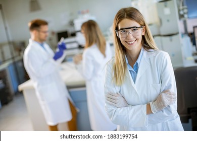 Young Female Scientist In White Lab Coat Standing In The Biomedical Lab