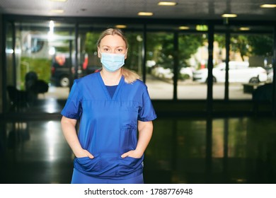Young Female Scrub Nurse Wear Blue Uniform And Face Mask, Standing In Hospital Hallway