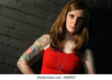 A Young Female With Serious Stare And Upper Arm Tattoo.