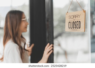 Young female shop owner about to walk in the door of her shop with Closed sign hanging on the glass door - Powered by Shutterstock