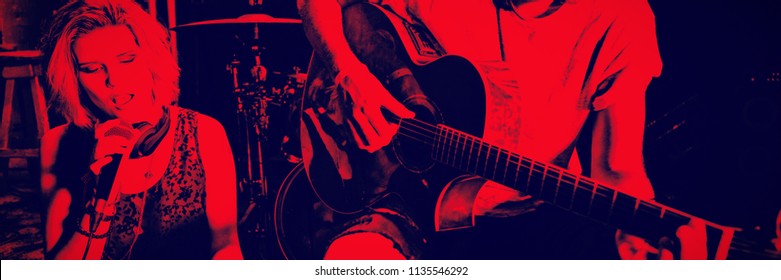 Young female singer with guitarist holding digital tablet on stage at nightclub - Powered by Shutterstock