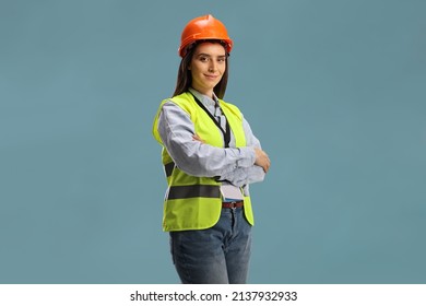 Young female site engineer with a safety vest and hardhat isolated on blue background