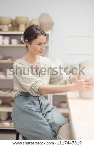 Similar – Image, Stock Photo Young female sitting by table and making clay or ceramic mug