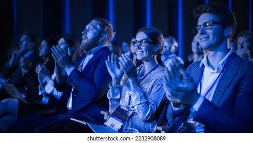 Young Female Sitting in a Crowded Audience at a Science Conference. Delegate Cheering and Applauding After an Inspirational Keynote Speech. Auditorium with Young Successful Specialist.