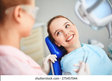 Young Female Sitting In Dentist Office And Looking At Her Doctor With Smile