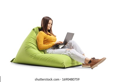 Young Female Sitting On A Bean Bag Chair And Using A Laptop Isolated On White Background