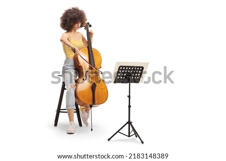 Young female sitting on a chair and playing a contrabass with a music sheet a stand isolated on white background