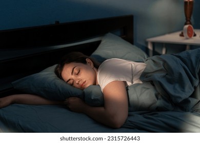Young female sleeping peacefully in her bedroom at night. Relaxing at nighttime. Copy space